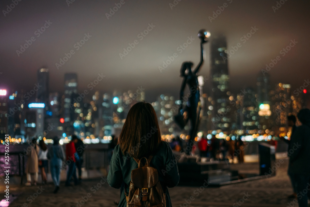 Young woman traveler is visiting at Avenue of Stars at night in Hong Kong China