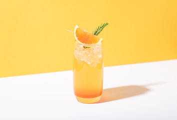 Cold and refreshing orange punch cocktail with orange slice on yellow background. summer drink.