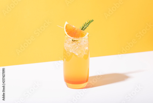 Cold and refreshing orange punch cocktail with orange slice on yellow background. summer drink. photo