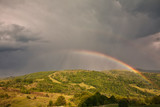 Beautiful mountain valley with green hills and huge rainbow