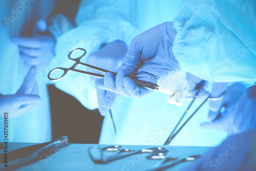 Surgeons hands holding surgical scissors and passing surgical equipment, close-up. Health care and veterinary concept