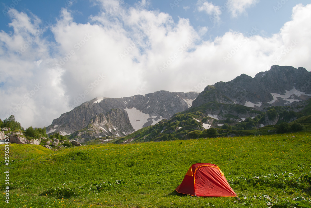 Red tourist tent is against mountains