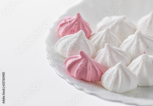 White-pink meringues on a white plate on a white background. 