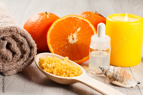 Oranges, towel, sea shell, bottle with aromatherapy oil, wooden spoon with sea salt and burning candle.