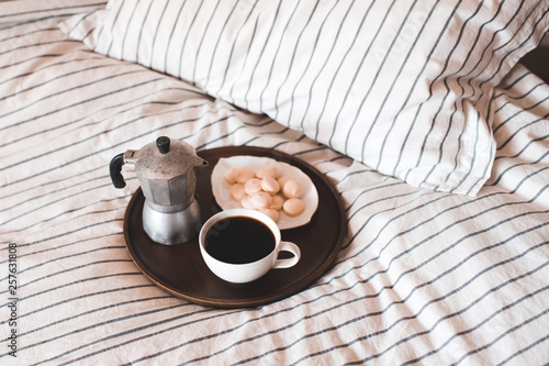 Cup of coffee with coffee maker on wooden tray in bed closr up. Breakfast. Good morning. photo