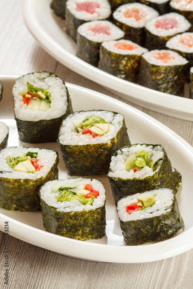 Different sushi rolls on ceramic plates and chopsticks. Different sushi rolls on ceramic plates and chopsticks.