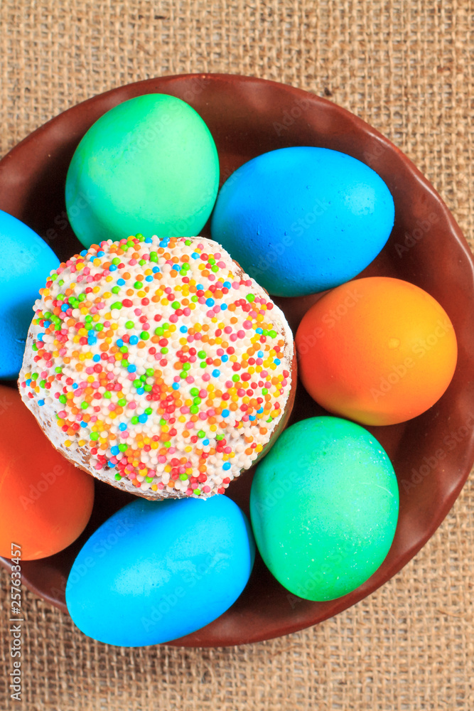 Easter cake and painted eggs on a plate with sackcloth on the background. Easter cake and painted eggs on a plate with sackcloth on the background.
