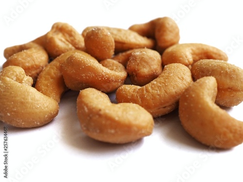 Roasted cashew nuts with salt. Isolated on white. Macro photography.