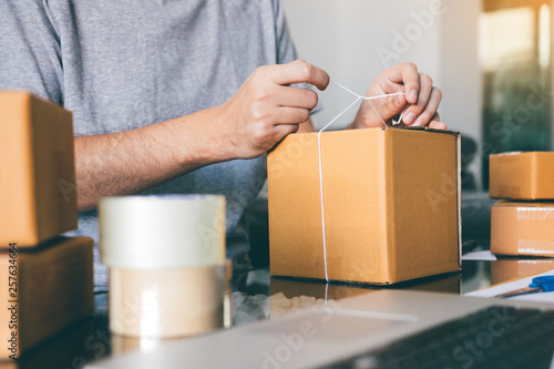 Asian young teenager owener of small business packing product in boxes preparing it for delivery. © wutzkoh