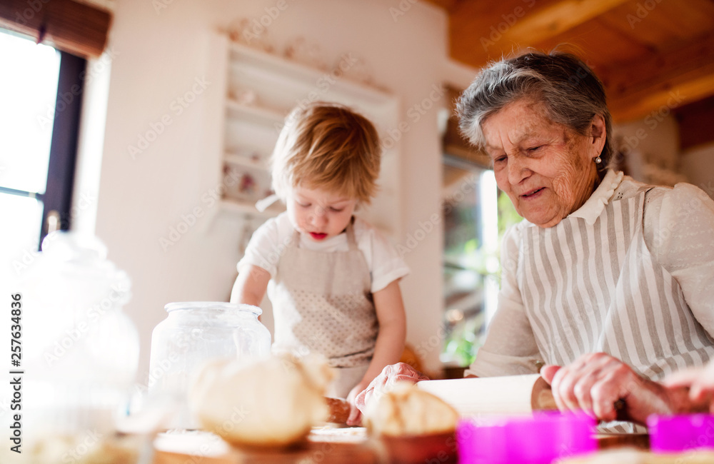 Senior grandmother with small toddler boy making cakes at home. Senior grandmother with small toddler boy making cakes at home.
