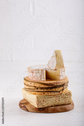 Stack of soft French cow's milk cheese on a cutting board on white. Camembert, Livarote, Pont-L'eveque cheese from Normandy. Copy space. photo