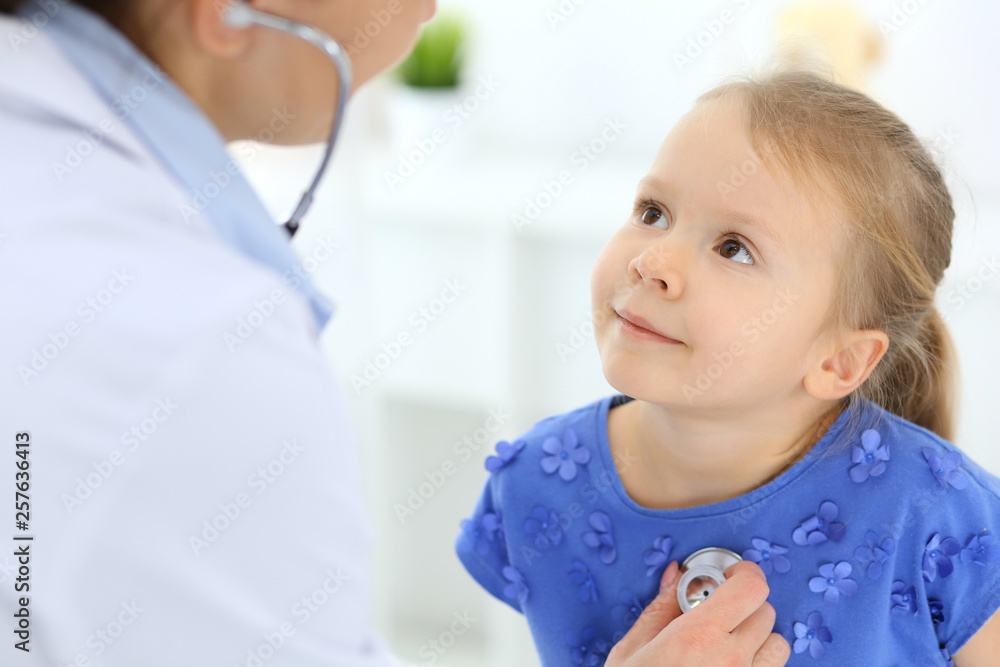 Doctor examining a little girl by stethoscope. Happy smiling child patient at usual medical inspection. Medicine and healthcare concepts Doctor examining a little girl by stethoscope. Happy smiling child patient at usual medical inspection. Medicine and healthcare concepts