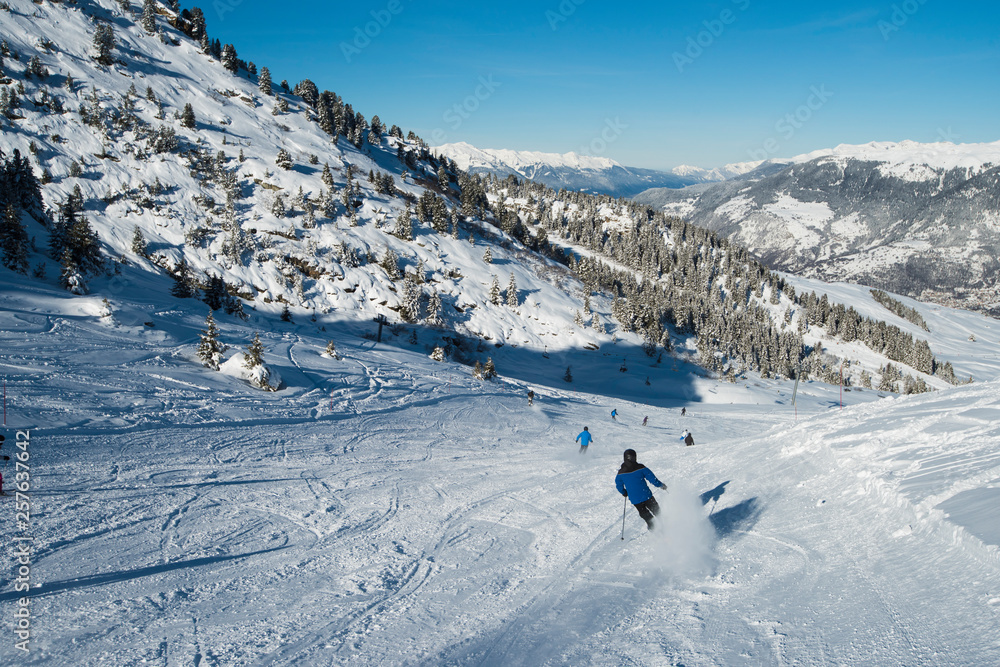 Skiers on a piste in alpine ski resort