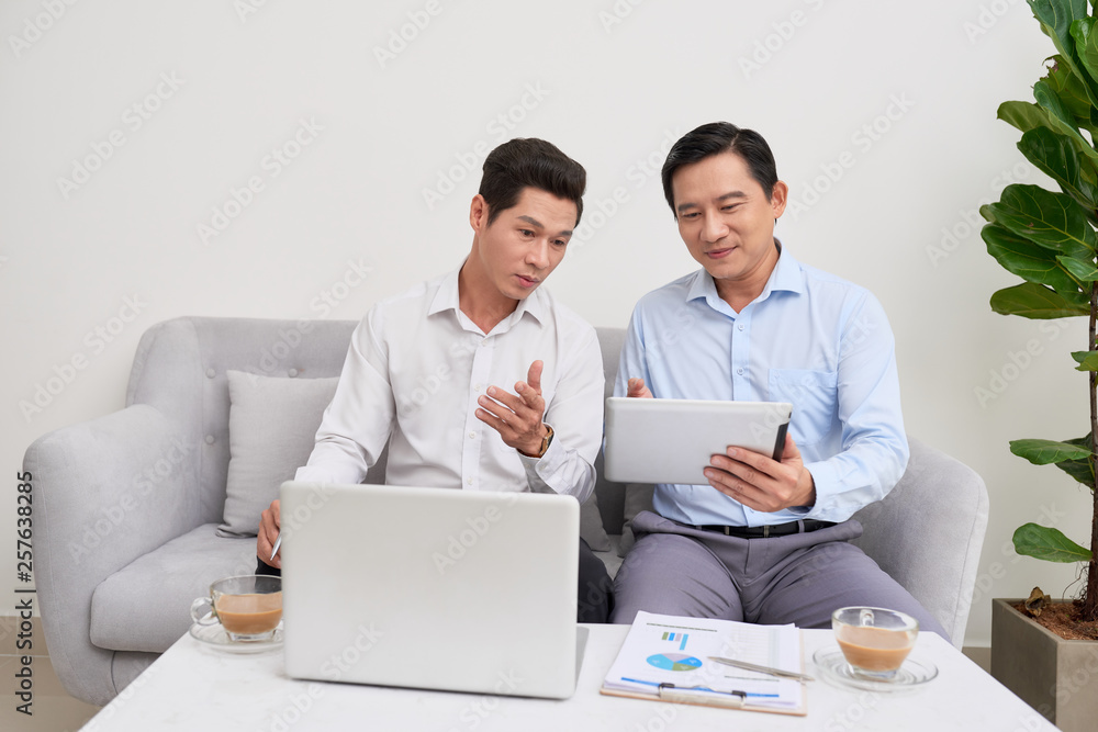 Handsome businessman smiling while working with a laptop at home Handsome businessman smiling while working with a laptop at home
