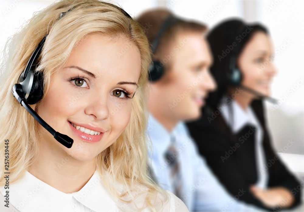 Female call center employee with coworkers on background Female call center employee with coworkers on background