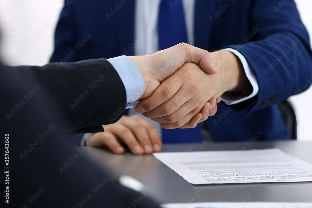 Business people shaking hands, finishing up a papers signing. Meeting, agreement and lawyer consulting concept Business people shaking hands, finishing up a papers signing. Meeting, agreement and lawyer consulting concept
