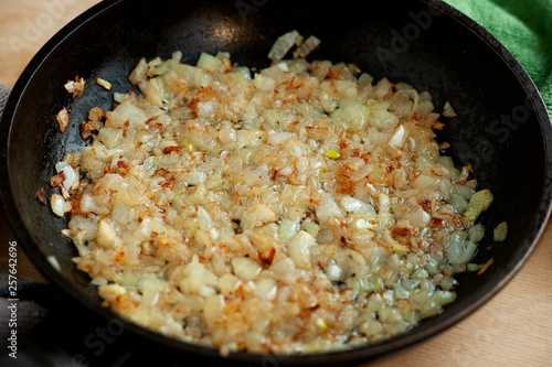 Fried onion in the pan. Macro. Cook onions in a pan for a dish. Stewed onions close-up. Cooking vegetables in a pan.