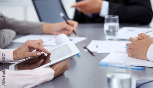 Woman hands using tablet at meeting. Business people group working together in office, close-up. Negotiation and communication concept