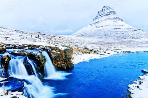 View of the Kirkjufell Mountain and Kirkjufellsfoss waterfall in Iceland on a cloudy day in winter. photo