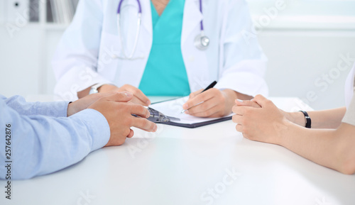 Doctor and patient couple are discussing something  just hands at the table