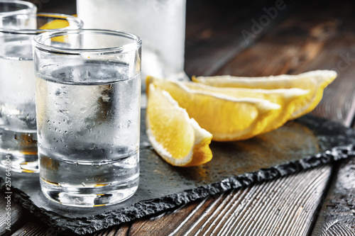 Fotografia Vodka in shot glasses on rustic wood background