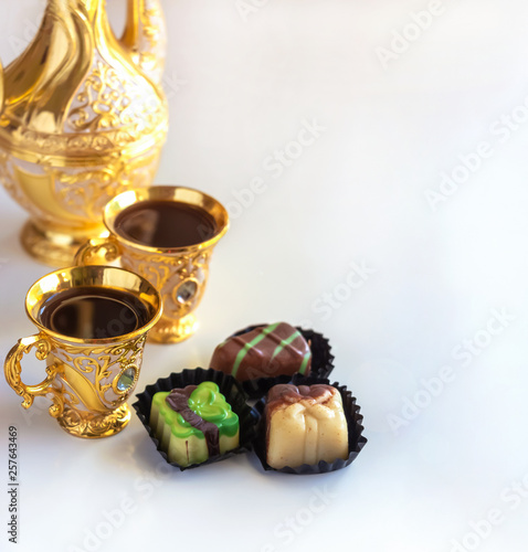 Still life with traditional golden arabic coffee set with dallah, cup and chocolate candy. White background.