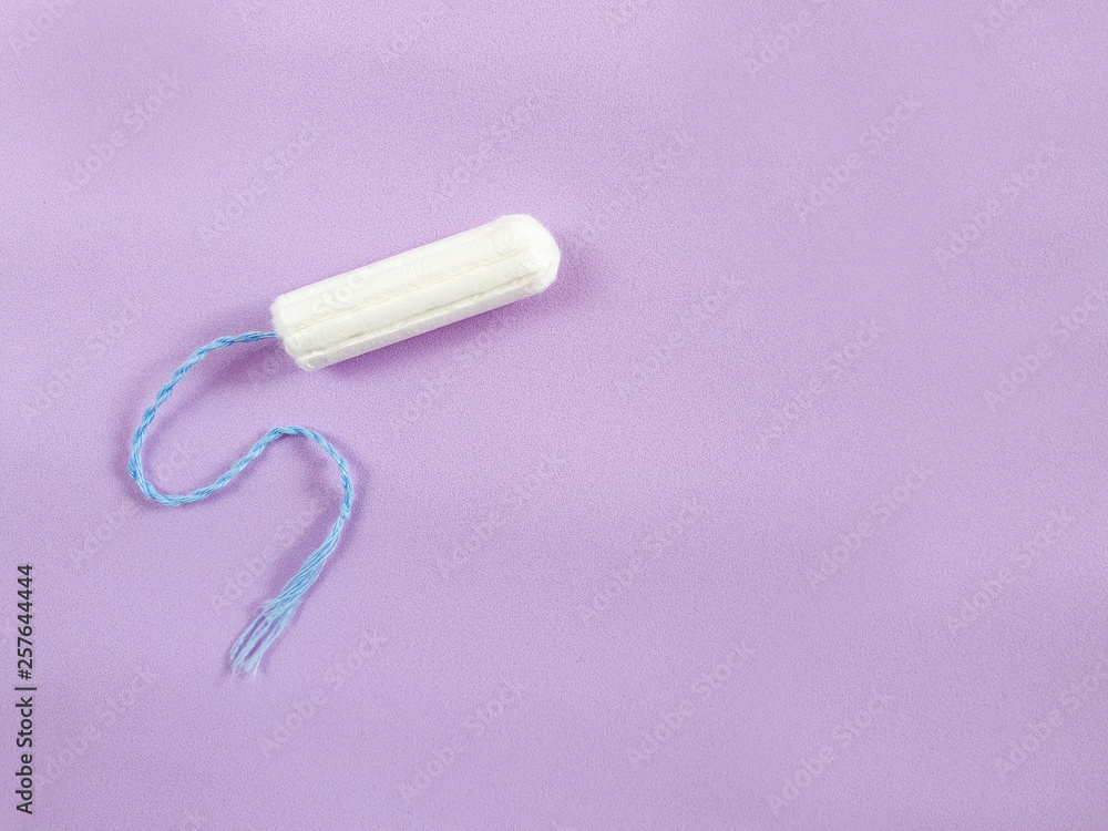 one cotton tampon on purple background. Menstrual cycle period concept. Woman days hygiene protection. Top view, flat lay. one cotton tampon on purple background. Menstrual cycle period concept. Woman days hygiene protection. Top view, flat lay.