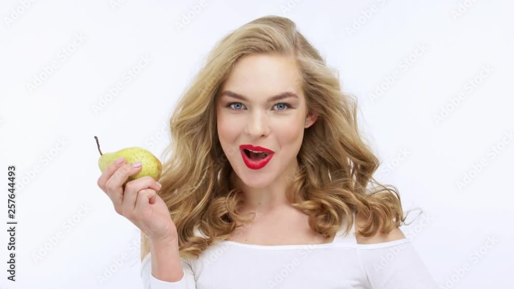 Young beautiful woman eating fruit and says yum. Happy adult girl eats pear. Young beautiful woman eating fruit and says yum. Happy adult girl eats pear.