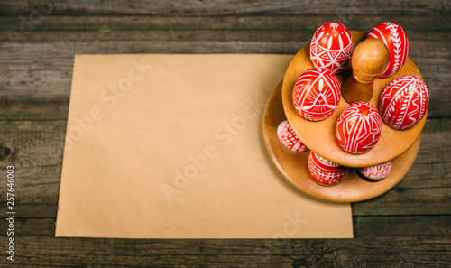 Easter eggs with folk white pattern lay around stand for eggs standing on wood board. Closeup horizontal background