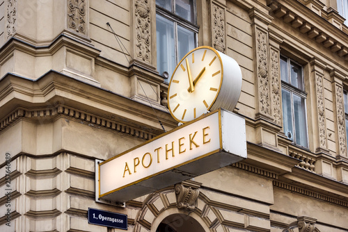 Canvas Print Austria, Vienna: Street scene with traditional old famous pharmacy with sign and clock on house facade in the city center of the Austrian capital - concept Aphotheke health illness