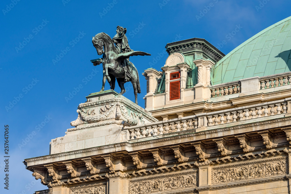 Austria, Vienna, Opernring: Roof top of the famous Vienna State Opera (Wiener Staatsoper) with rider on pegasus statue in the city center of the Austrian capital with blue sky - concept travel music