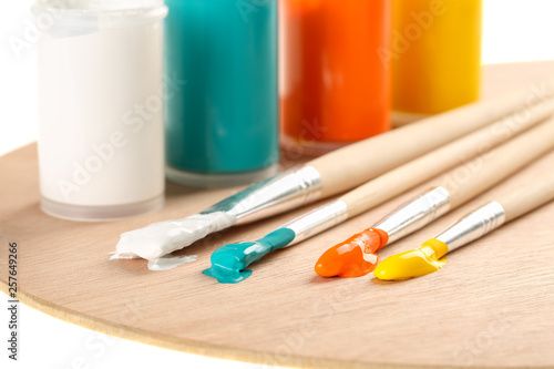 Extreme close up of art paint brushes with acrylic paint in vivid summer colors on a wooden palette