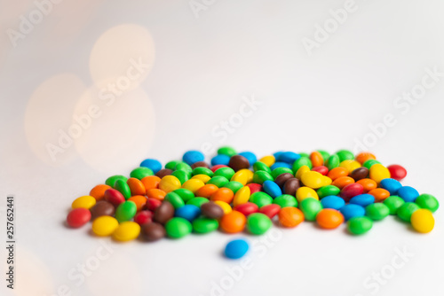 Coated chocolate multicolor candies on the white background with bokeh lights