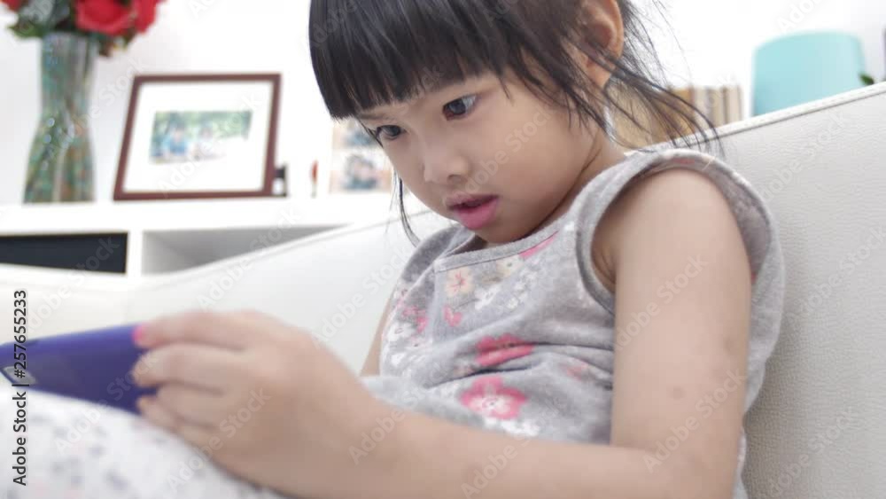 Little asian girl watching on cell phone with smile face at home. Little asian girl watching on cell phone with smile face at home.