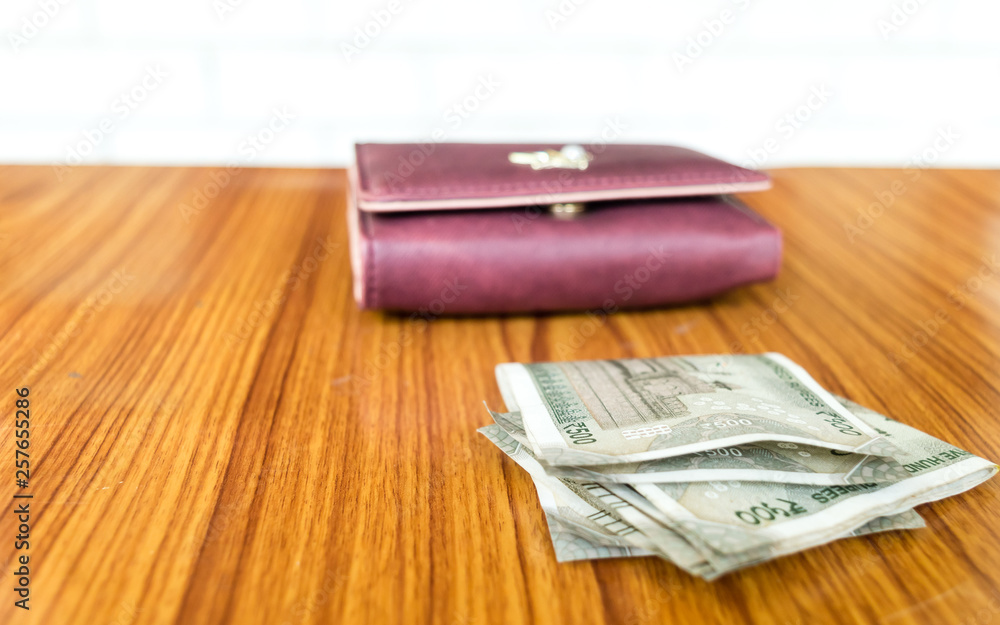 Indian five hundred (500) rupee cash note in brown color wallet leather purse on a wooden table. Business finance economy concept. Side angel view with copy space room for text on left side of image. Indian five hundred (500) rupee cash note in brown color wallet leather purse on a wooden table. Business finance economy concept. Side angel view with copy space room for text on left side of image.