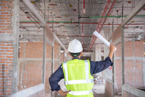 Engineering Consulting People on construction site holding blueprint in his hand. Building inspector. Construction site check drawing