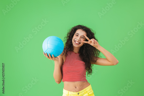 Image of delighted woman 20s wearing summer clothes smiling and holding volley ball © Drobot Dean