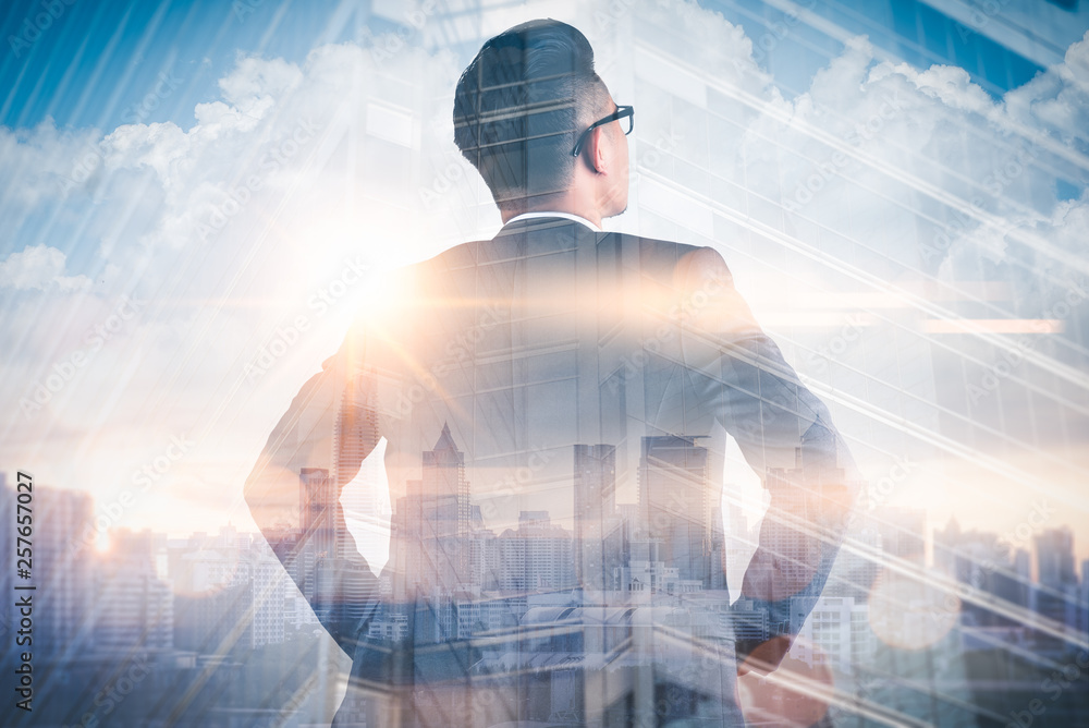 The double exposure image of the businessman standing back during sunrise overlay with cityscape image. The concept of modern life, business, city life and internet of things. - obrazy, fototapety, plakaty 