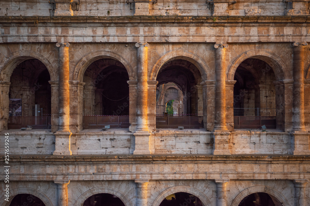 Fragment of a wall with arched windows of Great Colosseum (Coliseum, Colosseo) at sunset. Rome, Italy.
