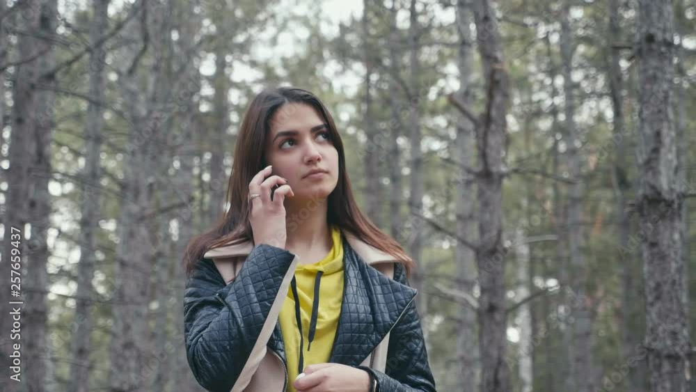 Glamour girl seeking a signal to call from her phone in a pine forest in slo-mo Glamour girl seeking a signal to call from her phone in a pine forest in slo-mo