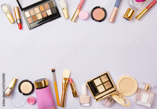 woman make up cosmetics on purple. Decorative cosmetics: highlighter, concealer, rouge, palette with eye shadows and brushes for face make up, face sculpture. Copy space. Gold and purple