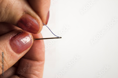 White elderly woman holding a needle and thread a narrow needle hole on a white background