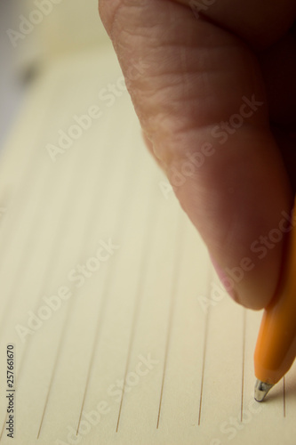 White elderly woman holding a needle on the middle finger wearing a thimble, the needle pierces the lilac textured fabric