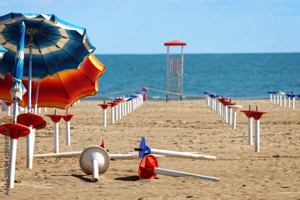 the clearance of the beach after the season with some parasol stands and the sea in the background the clearance of the beach after the season with some parasol stands and the sea in the background