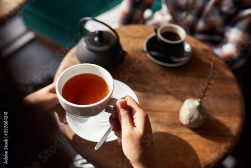 Woman about to drink tea while sitting in a cafe