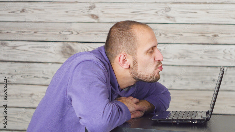 A short haired man kissing a computer screen. A short haired man kissing a computer screen.