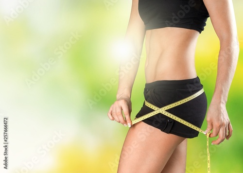 Young woman with measuring tape on her belly