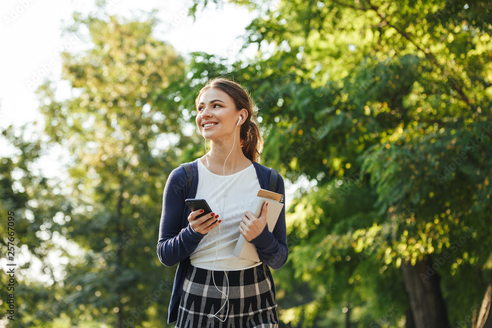 Cheerful young school girl walking outdoors
