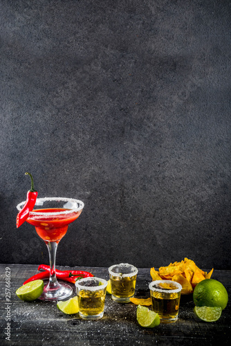 Cinco de Mayo celebration concept. 5th May Mexican party's drinks - margarita cocktail, tequila shots with lime, hot chili peppers and chips, dark background copy space photo