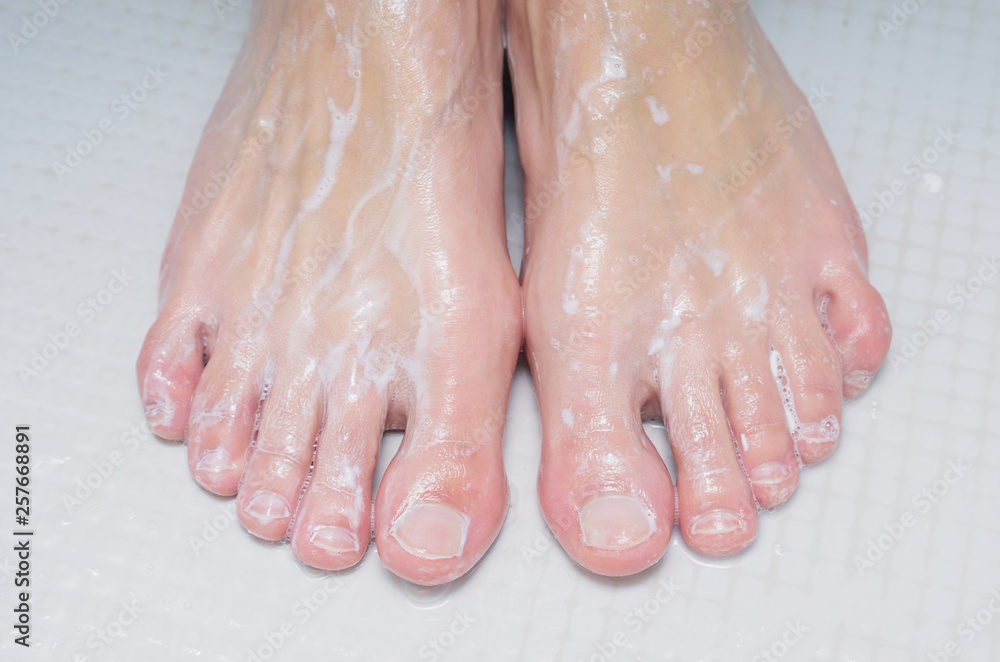 Legs of a young woman in the shower. Hygiene and washing feet. Close-up, part of body.